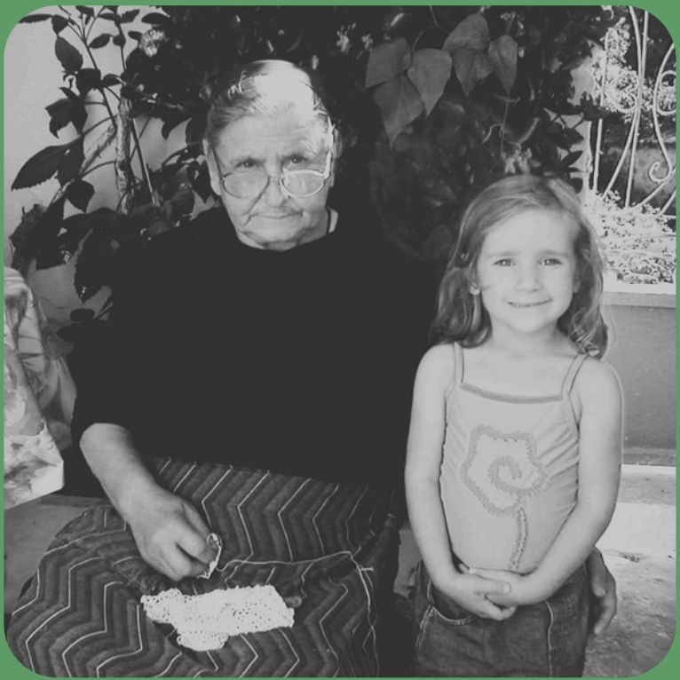 Stella as a child sitting beside her Greek grandmother, who is crocheting a doily